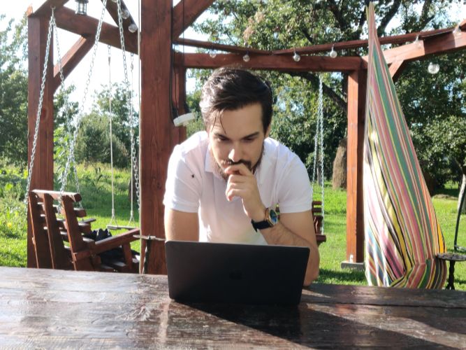 Alex looking at a laptop thinking